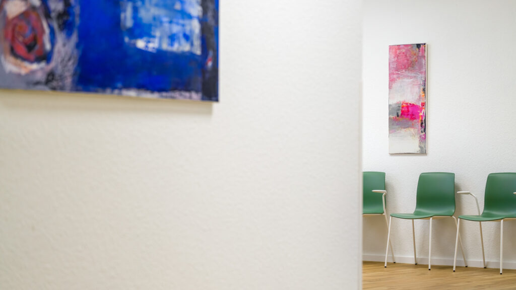 Wartebereich der Praxis mit einem blauen und einem pinkfarbenen Gemälde