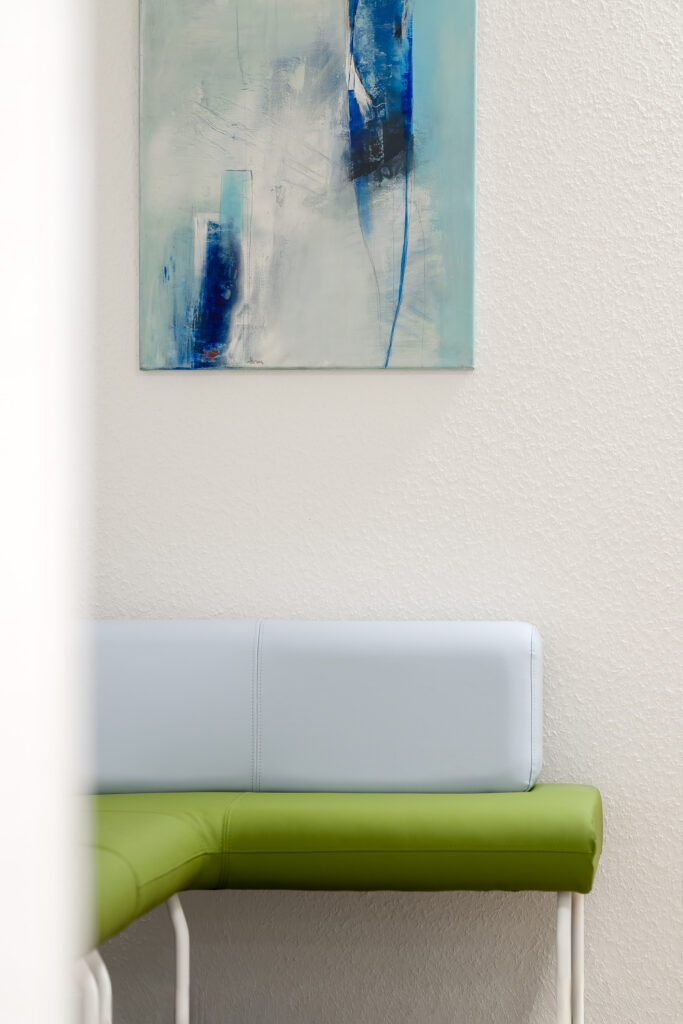 Sitzbank im Wartebereich unter einem blau-weißen Gemälde